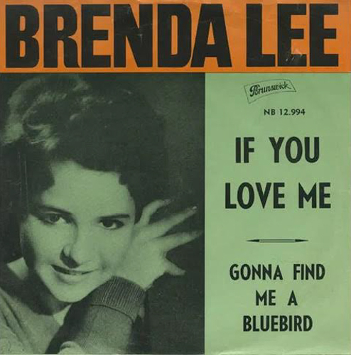 Brenda Lee laying on a huge cushion, heels kicked up behind her.