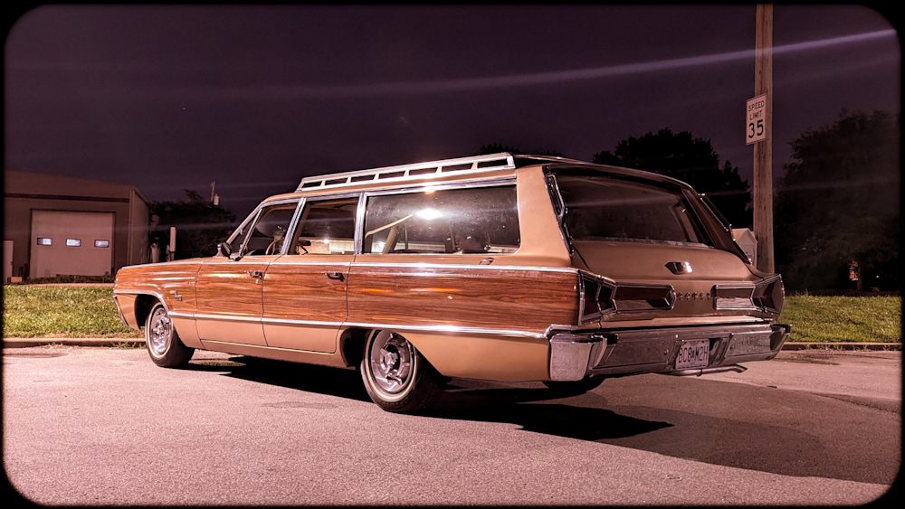 A very long, wood-sided station wagon pictured at night.